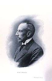 Head and shoulders profile of a man, facing left. His most prominent feature is his large hawk-like nose. He is dressed formally, with a stiff white wing collar.