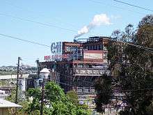 A large industrial building seen through trees.