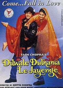 The Dilwale Dulhania Le Jayenge theatrical release poster shows a man in a black leather jacket and blue jeans holding over his shoulders a woman in a red wedding dress. A caption on top reads "Come ... Fall in Love".