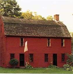 Simple, two-story wooden house. The two doors open directly on to the front lawn.