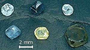 Six non-faceted diamond crystals of 2–3&nbsp;mm size; the diamond colors are yellow, green-yellow, green-blue, light-blue, light-blue and dark blue