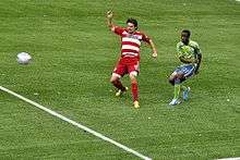 Zakuani vies against a Dallas player for the ball