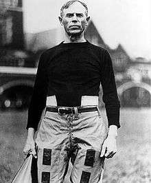 Heisman in his late forties wearing a jersey and lower pads