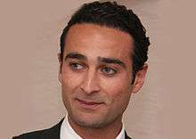 An image of Khaled Al Sabawi. He is a clean-shaven middle aged man, with slicked back black air and a smile. He is looking to the left of the camera.