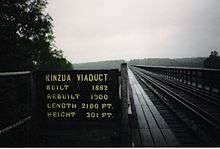 View across the bridge from the bridge deck. A sign indicating the bridge's construction year, reconstruction year, height and length is next to the bridge deck.