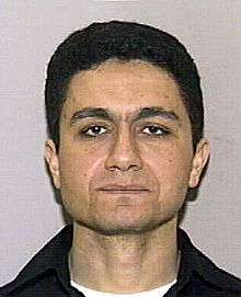 A head shot of a man in his thirties looking expressionless toward the camera