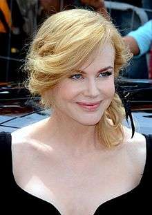 A photo of a woman smiling. She is wearing a black dress.
