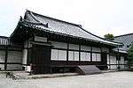 Wooden building with a hip-and-gable roof and white walls.