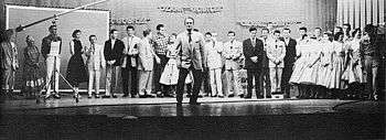 Cast of the show lined up against the back of the stage with Red Foley center-stage
