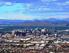 A photo showing the skyline of Phoenix, looking north. It shows the various buildings of the downtown area, as well as Sunnyslope Mountain in the background
