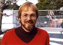A man in his 30s with beard and glasses