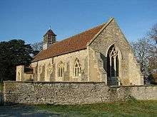 A stone church with a red tiled roof seen from the southeast. It has a south porch and a louvred belfry at the west end; there is no external division between the nave and the chancel