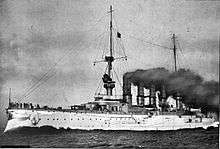 A large white warship with gray superstructure; several men are standing on the bow