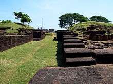 Ancient remains of stone walls with a grassy path in the middle
