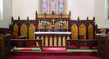Panoramic photograph of the hand carved and painted cedar woodwork in the St John's chancel, with red carpet
