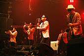 A picture of a group of men on a stage in white jackets performing jazz instruments.