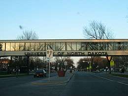A road facing a bridge that prominently displays "University of North Dakota