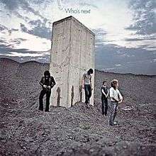 A photograph of The Who walking away from a stone monolith and zipping up their pants, with visible streaks of urine on the structure